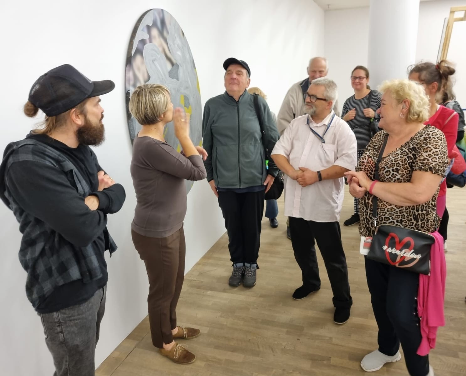 Grupa osób głuchych oraz tłumacz języka migowego podczas wystawy w Galerii Sztuki Współczesnej w Opolu.